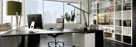 Um escritório moderno com uma grande mesa com um computador, uma luminária de mesa e material de escritório. O escritório conta com cadeira ergonômica preta, grande janela com vista para a cidade, estantes repletas de livros e decoração, luminária verde e plantas de interior.
