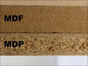 Um close de dois tipos de produtos de madeira projetada: a peça superior, rotulada como "MDF", apresenta uma superfície lisa e densa, enquanto a peça inferior, rotulada como "MDP", apresenta uma textura mais áspera com partículas de madeira visíveis.